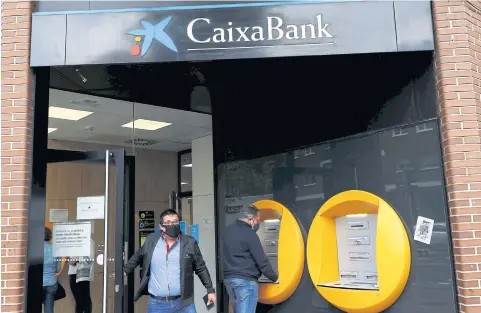  ?? REUTERS ?? A man walks out of a CaixaBank branch in Madrid on Tuesday.