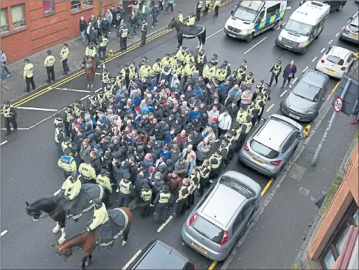  ??  ?? SURROUNDED: With mounted officers in front and behind, police contain a small group of supporters heading to the Old Firm derby match at Parkhead yesterday morning.