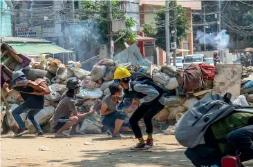  ?? AP ?? Anti-coup protesters abandon their makeshift barricades and run as armed riot policemen charge after firing teargas and rubber bullets.
