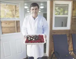  ?? CP PHoTo ?? Assam Hadhad, a Syrian refugee who arrived in Canada last year, displays a tray of chocolates at his shop, Peace by Chocolate, in Antigonish.