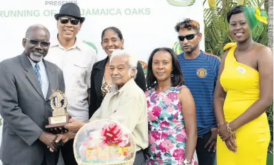  ?? FILE ?? Harry Jaghai (centre) receives a trophy from Dr St Aubyn Bartlett (left) following Amerth Robles’ win aboard SECRET TRAVELLER in the 2017 Jamaica Veterinary Board World Vet Day race at Caymanas Park, on Saturday, April 29, 2017.