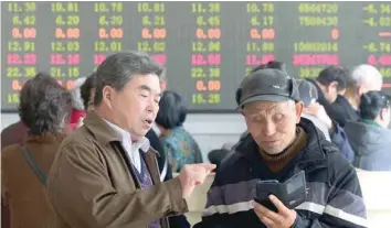  ?? — Reuters ?? Investors check stock informatio­n on a mobile phone at a brokerage house in Shanghai, China.