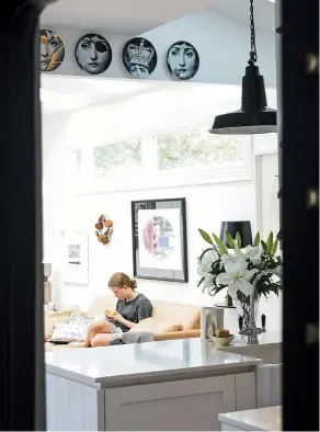  ??  ?? ABOVE LEFT Tracy’s daughter Esme relaxes on the pale leather Simon James sofa that keeps getting better with age; a collection of Fornasetti plates hangs above the kitchen bench. ABOVE RIGHT Esme uses the snug as a chill-out zone and it’s mostly become her special space, especially when she’s with friends; the artwork is Trance Sleep and Shudder by Paul Martinson, the lamp and side table are both from ECC and the antique silver cigar box was a wedding present and now houses chess pieces.