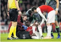  ?? PHOTO: REUTERS ?? Arsenal’s Danny Welbeck receives treatment from medical staff after sustaining an ankle injury during his team’s Europa League group E match against Sporting at Emirates Stadium in London yesterday.