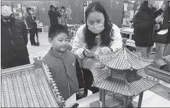  ?? QIU JIER /FOR CHINA DAILY ?? Top: A visitor shows her son the structure of a wooden architectu­re model at the exhibition of intangible cultural projects at the Confucius Museum on Wednesday.