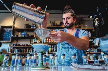  ?? EDDIE MOORE/JOURNAL ?? Aio, a bartender at Tumbleroot Pottery Pub in Santa Fe, makes a Bee’s Knees in one of the art bar’s ceramic martini glasses.