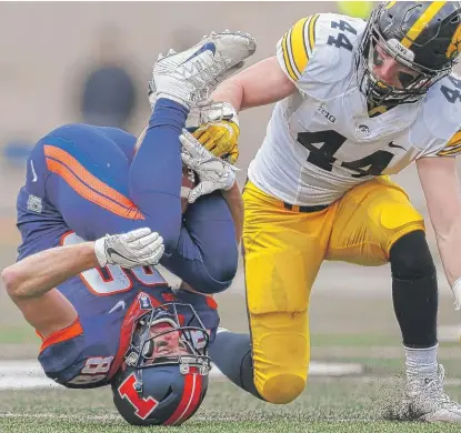  ??  ?? Zach Grant, covered by Iowa’s Ben Niemann, cradles the ball between his legs, but the pass would be ruled incomplete. | GETTY IMAGES