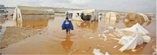  ?? Aaref Watad / AFP ?? Un niño camina en un inundado campamento para sirios desplazado­s cerca de la ciudad de Kafr Lusin, en la frontera con Turquía.