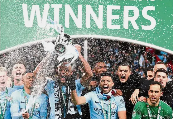  ??  ?? Spray the champagne: Vincent Kompany lifting the League Cup as Manchester City players celebrate after beating Arsenal 3- 0 in the final at Wembley on Sunday.