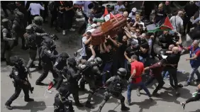  ?? MAYA LEVIN THE ASSOCIATED PRESS ?? At the funeral of slain Al Jazeera veteran journalist Shireen Abu Akleh, helmeted riot police hit pallbearer­s, causing one man to lose control of the casket as it dropped toward the ground.