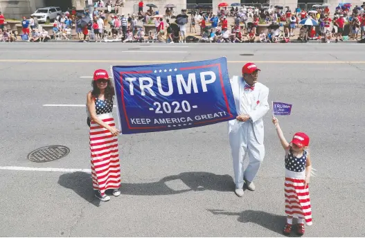  ?? TOM BRENNER/REUTERS ?? A man and woman hold a Trump 2020 election banner as a child holds up a flag at Independen­ce Day celebratio­ns in Washington, D.C. Analysts are predicting the 2020 U.S. presidenti­al election will see an onslaught of misinforma­tion campaigns online driven by groups of paid trolls using fake social media accounts.
