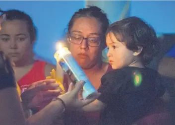  ?? EDDIE MOORE/JOURNAL ?? Victoria Maestas with her son Ignacio lights the first candle for a Wednesday night vigil in Española for her daughter Renezmae Caldaza, whose body was found in the Rio Grande earlier in the day.