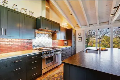  ?? Shuttersto­ck ?? Dark kitchen cabinetry can lend a cozy aesthetic to an interior, according to designers.