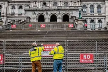  ?? Jim Franco / Special to the Times Union ?? State Office of General Service workers hang a sign on a newly installed fence at the state Capitol in Albany, warning people that the stairs are structural­ly unstable.