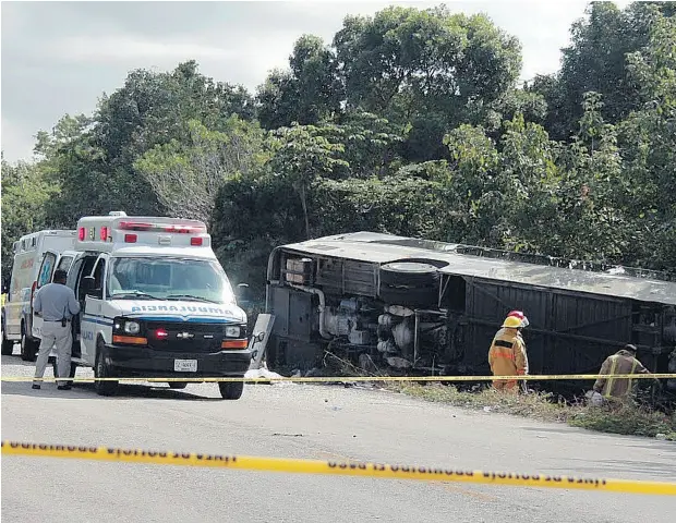  ?? NOVEDADES DE QUINTANA ROO VIA THE ASSOCIATED PRESS ?? An ambulance sits parked next to an overturned bus in Mahahual, Quintana Roo state, Mexico, on Tuesday. The bus carrying cruise ship passengers to the Mayan ruins at Chacchoben in eastern Mexico flipped over on a highway, killing 12 people. A Canadian...