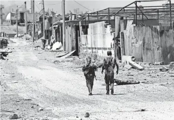  ?? HUSSEIN MALLA, AP ?? U.S.-backed Syrian Democratic Forces fighters walk past destroyed shops on the front line of the industrial district on the eastern side of Raqqa, Syria, on Wednesday.