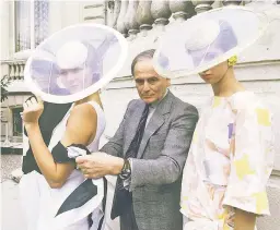  ??  ?? Cardin, seen here with two models in 1984, is the subject of a new solo exhibit at the Brooklyn Museum. Since the 1960s, the Parisian couturier was captivated by the idea of space travel, and designed far-out duds for the planet-hopping fashionist­as of the future.