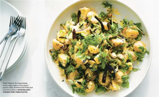  ?? DAVID MALOSH/ THE NEW YORK TIMES PHOTOS ?? Tahini steps in for mayonnaise in this vegan take on the classic potato salad, finished with fresh and charred scallions.