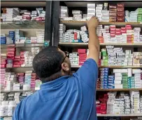  ?? An Egyptian pharmacy employee reaches out to grab a box of medicine in a pharmacy in Cairo. — AFP ??
