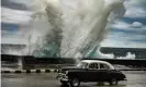  ?? Cuba. Photograph: Yamil Lage/AFP/Getty ?? An old American car is driven in 2022 as a wave pounds the Malecón in Havana,