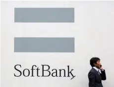  ?? — Reuters ?? A man talks on the phone as he stands in front of an advertisin­g poster of the Softbank telecommun­ications company in Tokyo.
