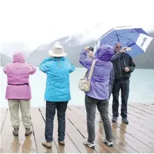  ?? PHOTOS: COLLEEN DE NEVE/ CALGARY HERALD ?? Tourists line up to take photos at Lake Louise on Thursday. The falling Canadian dollar is making Alberta’s national parks attractive destinatio­ns for foreign visitors.