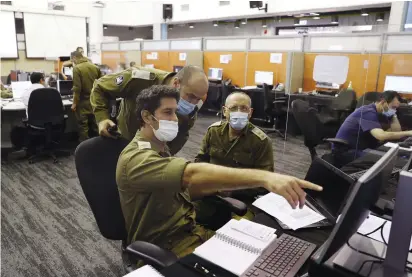  ?? (Ronen Zvulun/Reuters) ?? SOLDIERS WORK at the IDF’s Alon Command Center in Ramle as they conduct epidemiolo­gical investigat­ions as part of the army’s effort to trace chains of infection to curb the spread of the coronaviru­s.