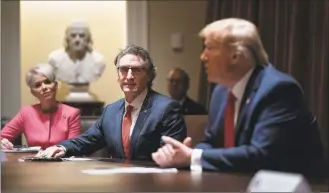  ?? Evan Vucci / Associated Press ?? Michelle Kommer, commission­er of the North Dakota Department of Commerce, left, and North Dakota Gov. Doug Burgum, center, listen as President Donald Trump speaks during a meeting about the coronaviru­s response, in the Cabinet Room of the White House on Wednesday.