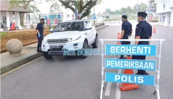  ??  ?? Police personnel man a roadblock in Kuching city during the MCO in March.