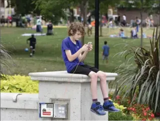  ?? JOHN RENNISON, THE HAMILTON SPECTATOR ?? Eyes down: Diego Codyre, 12, plays Pokemon while plugged into an electrical outlet next to the Gage Park fountain.