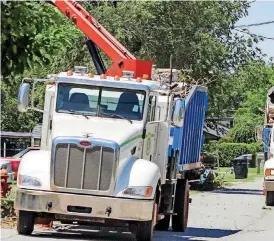  ?? [PHOTOS BY THOMAS MAUPIN, FOR THE OKLAHOMAN] ?? All three of Moore’s “Terminator” grapple trucks were working last week on Poplar Drive. One of the drivers said he and his co-workers have to watch out for sagging power lines such as those above the truck pictured at right.