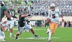  ?? AP ?? Arizona State quarterbac­k Jayden Daniels, right, scrambles for a first down against Michigan State's Joe Bachie (35) and Kenny Willekes (48).