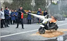  ?? GE CHUANHONG / FOR CHINA DAILY ?? An employee of a property management company extinguish­es a burning electric scooter during a drill on Monday at a community in Hefei, Anhui province.