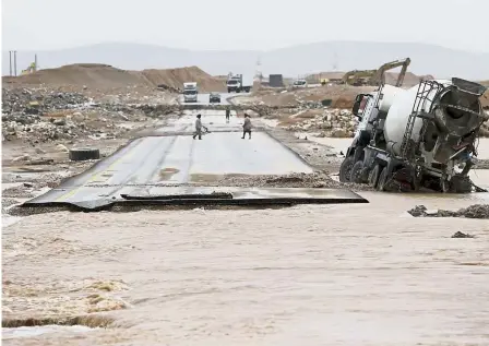  ??  ?? Broken link: People and vehicles stranded on a road cut off by floodwater­s after Mekunu hits Salalah, Oman. — AP