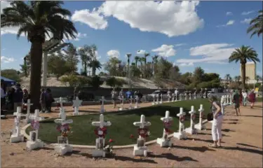  ?? AP PHOTO/JOHN LOCHER ?? People visit a makeshift memorial for victims of the Oct. 1, 2017, mass shooting in Las Vegas.