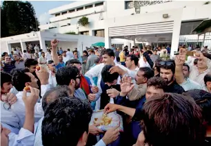  ?? AP ?? Supporters of the Pakistan Tehreek-e-Insaf share sweets to celebrate the success of their leader Imran Khan outside the National Assembly in Islamabad on Friday. —