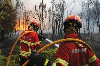  ?? The Associated Press ?? WILDFIRE: Portuguese firefighte­rs work to stop a forest fire from reaching the village of Figueiro dos Vinhos on Sunday in central Portugal. Portugal’s president says the country’s pain “knows no end” as it mourns at least 61 people killed in the...