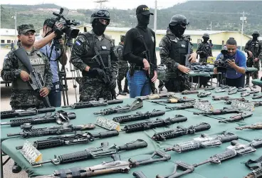  ?? ORLANDO SIERRA / AFP / GETTY IMAGES ?? Police and military personnel display an assortment of assault rifles and ammo seized from members of the Barrio 18 and Mara Salvatruch­a gangs during a raid last year.