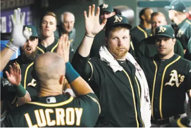  ?? Mike Stone / Associated Press ?? Oakland starting pitcher Brett Anderson (center) congratula­tes catcher Jonathan Lucroy after he scored during the seventh inning of a 15-3 romp over Texas.