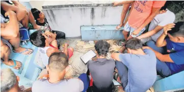  ??  ?? Suspected drug pushers and users sit beside tombs during the Philippine Drug Enforcemen­t Agency (PDEA) operatives’ anti-drug operations inside the cemetery in Quezon city, metro Manila, the Philippine­s. — Reuters photo