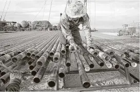  ?? Kirk McKoy / Los Angeles Times via Getty Images ?? An oil rigger prepares pipes at a Schlumberg­er field in Midland. The company says its onshore North American revenues jumped 42 percent from the first quarter.