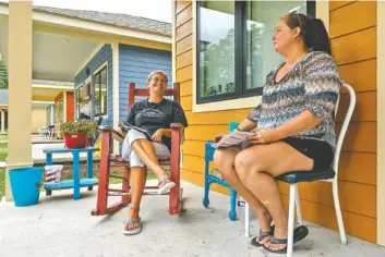  ?? STAFF PHOTOS BY DOUG STRICKLAND ?? Chassey Wooten, left, and Martha Massey sit on the porch of Wooten’s Chamberlai­n Avenue home on Wednesday. Wooten and Massey both live in homes on the street built by Tower Constructi­on partly through a city funding grant.