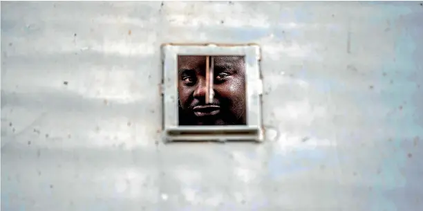  ?? AP ?? A supporter of Zimbabwean’s main opposition party MDC, who was arrested following clashes, is seen detained in a police vehicle outside the MDC headquarte­rs, in Harare.