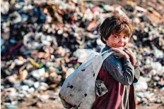  ?? AFP ?? A child holds a plastic bag while standing near a garbage ■ dump at a camp for those displaced by conflict in the countrysid­e near Syria’s northern city of Raqa.