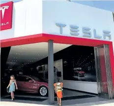  ?? JUSTIN SULLIVAN/GETTY IMAGES ?? People enter a Tesla showroom in Corte Madera, Calif. Tesla is raising $1.5 billion to ramp up production of the Model 3, its first mass market car.