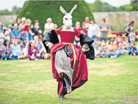  ??  ?? An actress entertains the crowd at Hampton Court Palace’s Henry VIII sporting academy. Until next Sunday visitors can join costumed characters to try jousting, firing a crossbow and other entertainm­ent of the Tudor era.