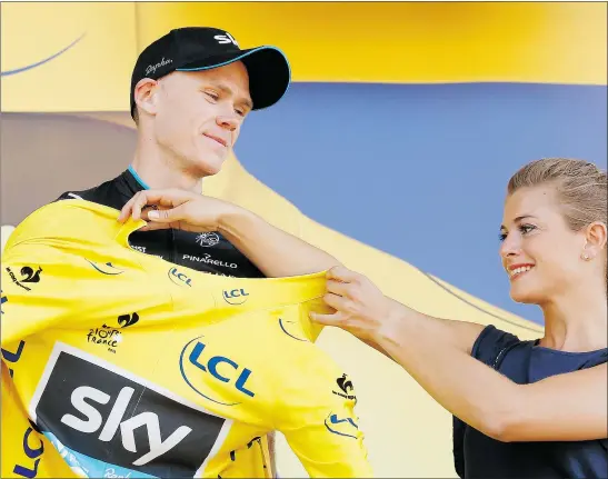  ?? — THE ASSOCIATED PRESS ?? Britain’s Chris Froome puts on the overall leader’s yellow jersey on the podium of the third stage of the Tour de France in Huy, Belgium on Monday. Crashes marred the race, causing several riders to quit the tour.