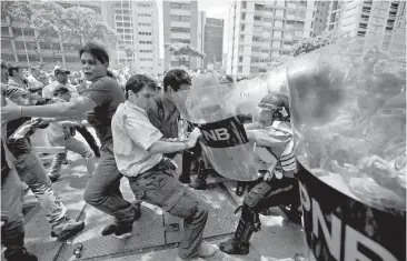  ??  ?? Demonstrat­ors fight with National Police officers during clashes near the congress building in Caracas, Venezuela, on Tuesday. Increasing­ly bitter divisions in Venezuela and other countries are straining the respect for the rule of law that is...