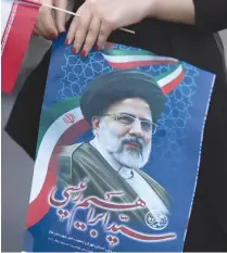  ?? (Majid Asgaripour/WANA/Reuters) ?? A SUPPORTER OF presidenti­al candidate Ebrahim Raisi holds a poster of him during an election rally in Tehran last week.