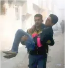  ?? WHITE HELMETS VIA AP ?? A member of the Syrian Civil Defense group carries a man who was wounded during airstrikes and shelling in Ghouta, a suburb of Damascus.
| SYRIAN CIVIL DEFENSE